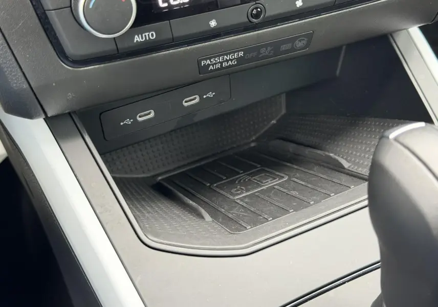 Détail de la console centrale du SEAT Arona 2025 avec zone de recharge sans fil et ports USB-C sous la climatisation.