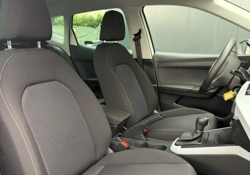 Intérieur avant du SEAT Arona 2025, vue côté droit, sièges tissu gris et console centrale avec boîte automatique.