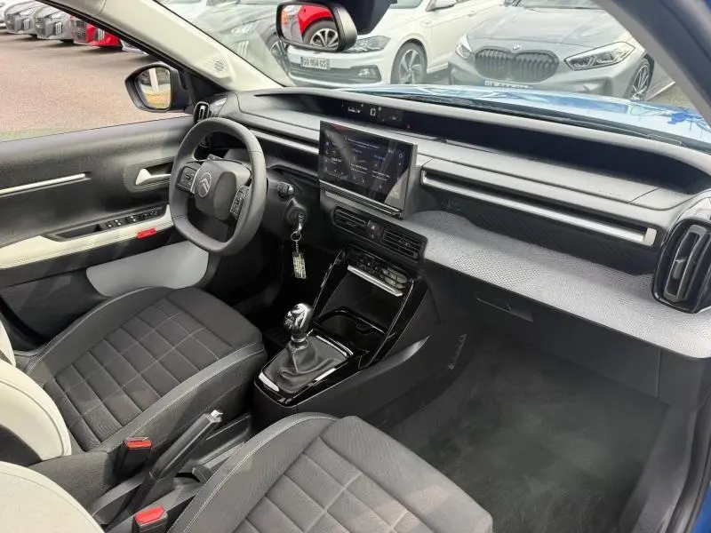 Vue intérieure côté conducteur de la Citroën C3 1.2 Turbo 100ch MAX 2025 avec boîte manuelle et sellerie noire.