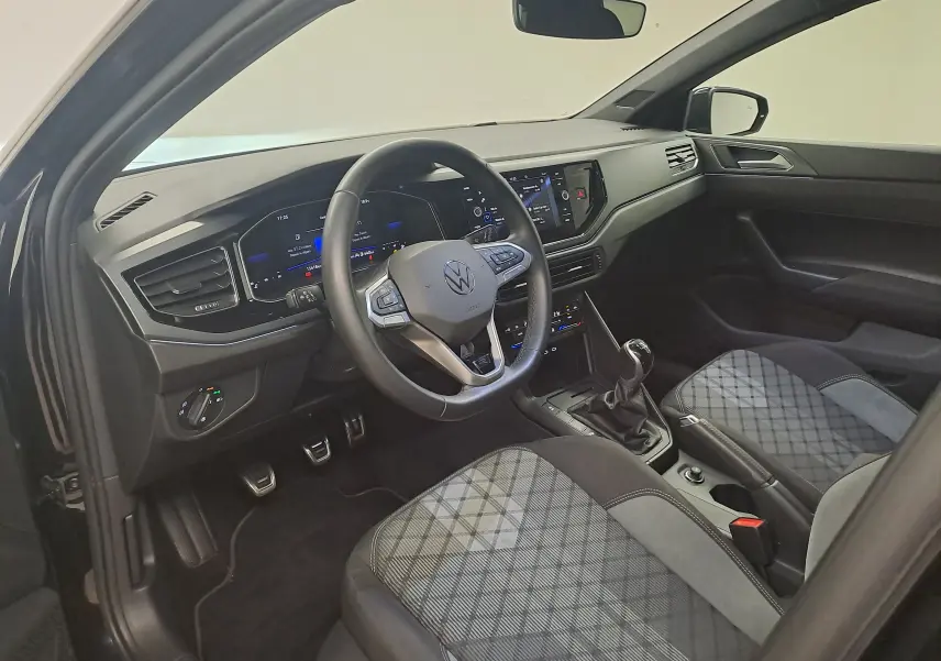 Vue intérieure côté conducteur de la Volkswagen Polo 1.0 TSI R-Line 2025 avec sellerie à motif écossais et boîte manuelle.