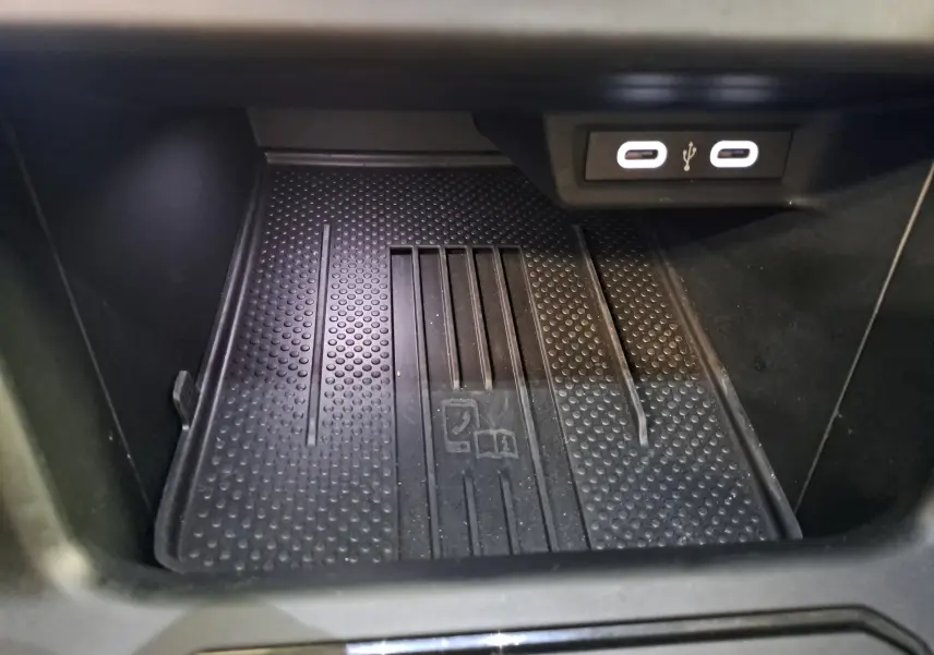 Gros plan sur le compartiment de rangement intérieur avec deux ports USB-C lumineux dans une Volkswagen Polo Noir Intense.