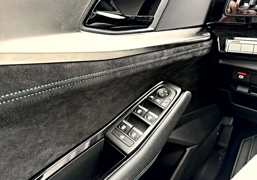 Détail de la porte côté conducteur du Renault Austral gris schiste, avec commandes de vitres et surpiqûres bleues.
