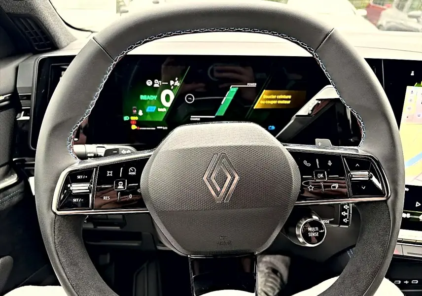 Vue frontale du volant noir du Renault Austral 2026 avec commandes multifonctions et écran numérique en arrière-plan.