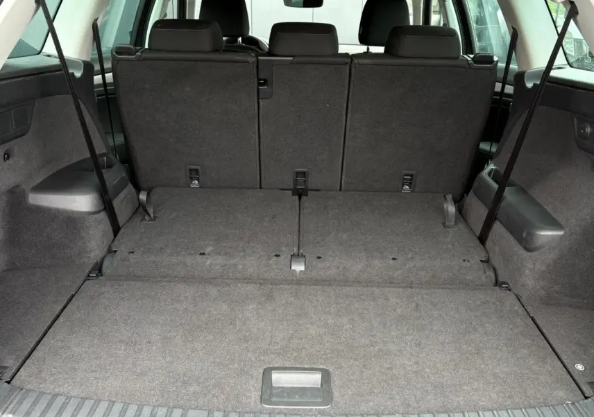 Coffre spacieux du Skoda Kodiaq 1.5 TSI 7 places, vue arrière avec sièges arrière rabattus, intérieur gris.