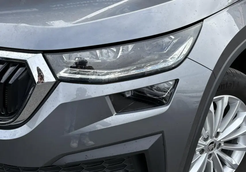 Gros plan sur l'avant droit du Skoda Kodiaq gris graphite, mettant en valeur le phare LED et la jante alliage 18 pouces.