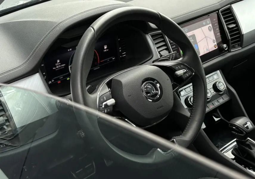 Vue intérieure rapprochée du volant et du tableau de bord numérique du Skoda Kodiaq 2024 avec console centrale et écran tactile.