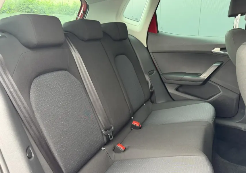 Vue intérieure côté droit des sièges arrière noirs du SEAT Arona Rouge Désir avec ceinture et appuie-têtes visibles.