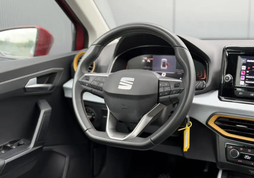 Vue intérieure centrée sur le volant du SEAT Arona 2025, avec détails du tableau de bord et touches multifonctions.