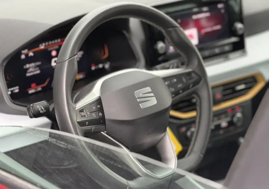 Vue rapprochée du volant noir du SEAT Arona TSI 115 Style 2025 avec tableau de bord digital et écran tactile.