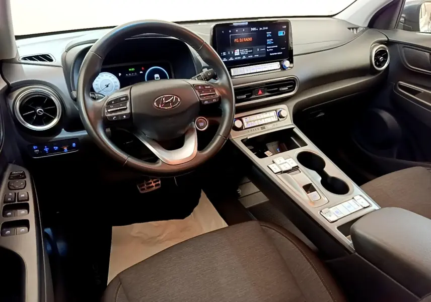 Intérieur de la Hyundai Kona électrique 2023 vu côté conducteur, volant cuir multifonctions et écran tactile central.