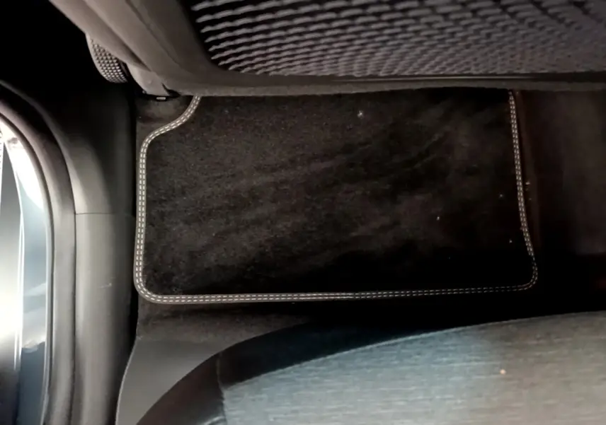 Vue intérieure du plancher côté passager avant avec tapis noir sur Hyundai Kona électrique bleu 2023.
