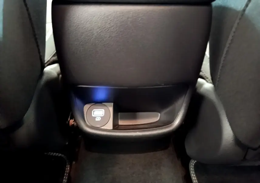 Prise USB arrière noire sous l'accoudoir central du Hyundai Kona électrique bleu 2023, vue rapprochée.