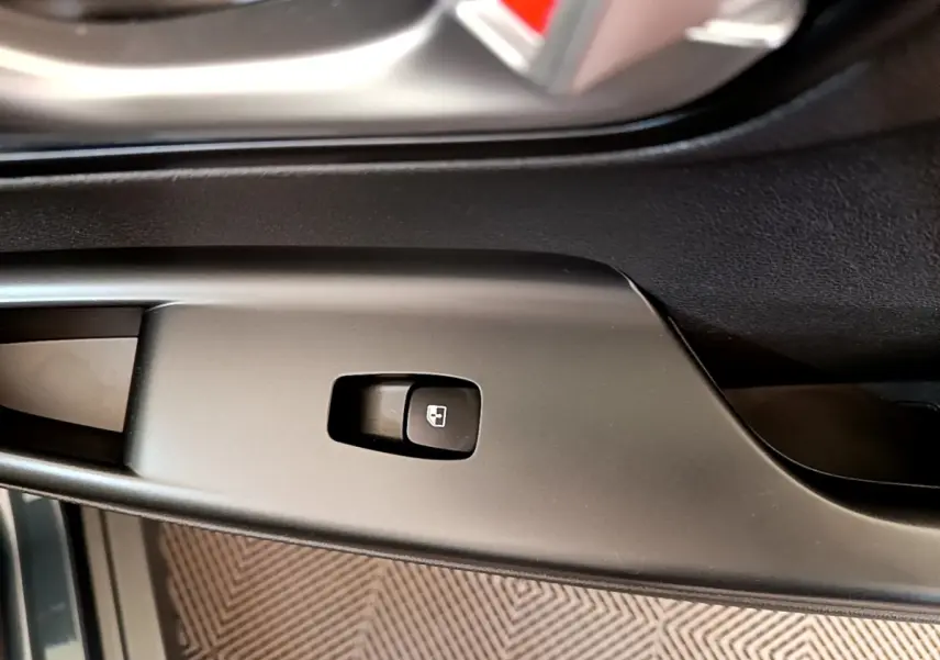 Gros plan sur le bouton de verrouillage des portes côté conducteur dans l'habitacle noir du Hyundai Kona bleu électrique 2023.