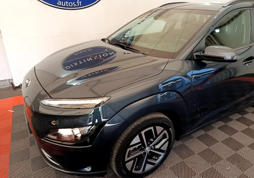 Vue 3/4 avant droit d'une Hyundai Kona électrique bleu foncé avec phares LED et jantes spécifiques.