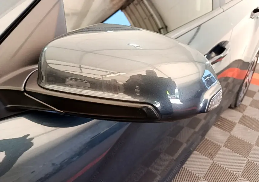 Rétroviseur droit bleu métallisé du Hyundai Kona électrique 2023 avec clignotant intégré, vue rapprochée en extérieur.