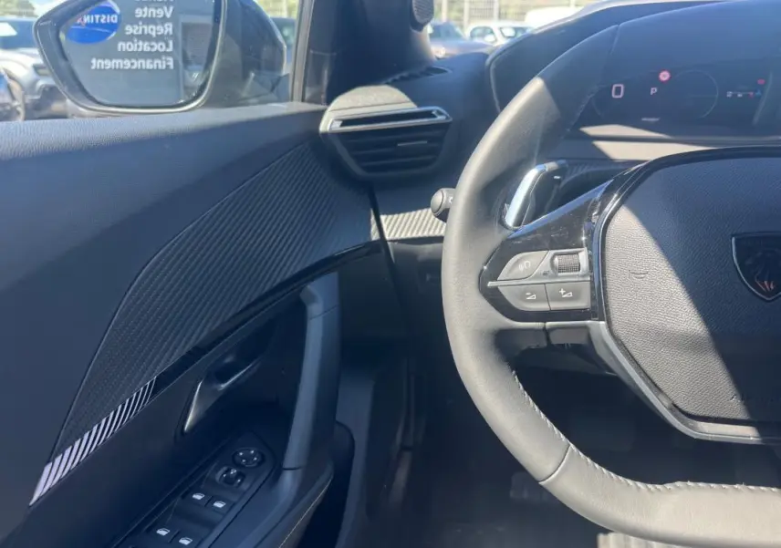Vue intérieure côté gauche du Peugeot 2008 Hybrid 136 e-DCS6 Allure 2025, volant et panneau de porte noirs avec détails modernes.