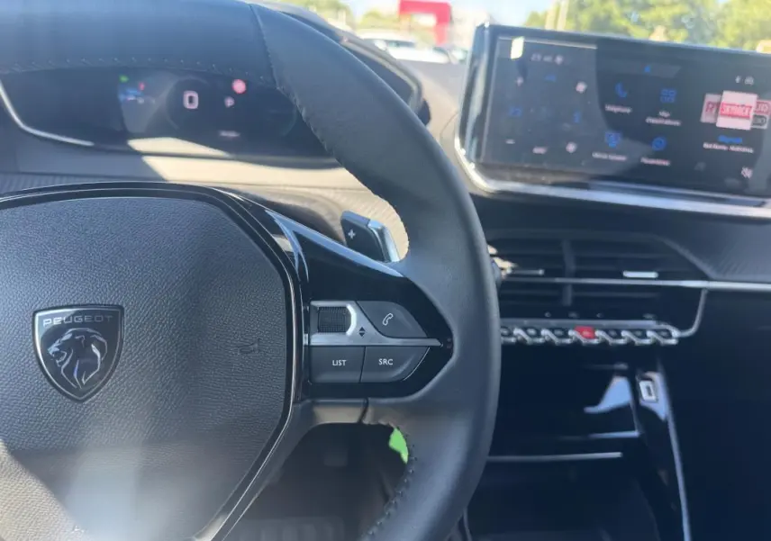 Vue rapprochée du volant noir de la Peugeot 2008 Hybrid 136 e-DCS6 Allure avec tableau de bord numérique et écran tactile.