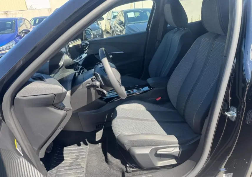 Vue intérieure côté conducteur du Peugeot 2008 Hybrid noir 2025, sièges tissu gris et tableau de bord moderne avec écran tactile.