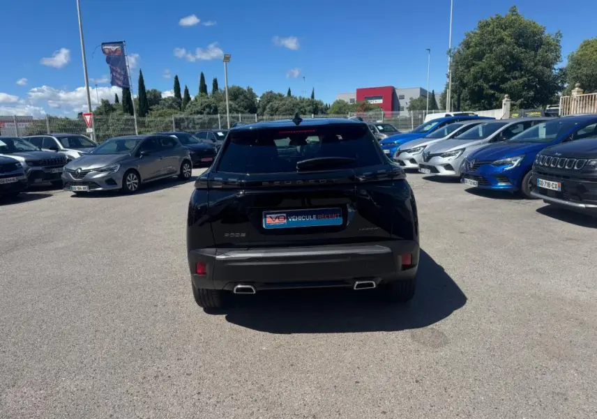 Vue arrière d'un Peugeot 2008 noir 2025 Hybrid 136 e-DCS6 Allure avec double sortie d'échappement et vitres teintées.
