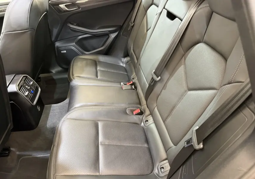 Vue intérieure côté droit des sièges arrière en cuir gris foncé du Porsche Macan 3.0 S avec aérations et ceintures visibles.