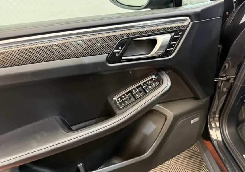 Vue rapprochée de la porte avant gauche du Porsche Macan 3.0 S gris foncé avec garniture carbone et commandes électriques.