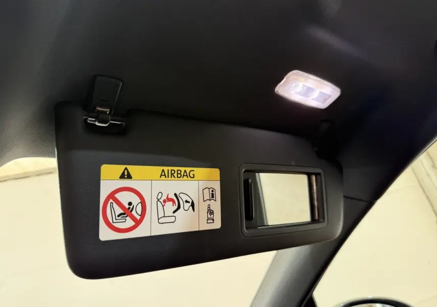 Détail du pare-soleil côté conducteur avec miroir et avertissement airbag dans un Porsche Macan gris foncé.