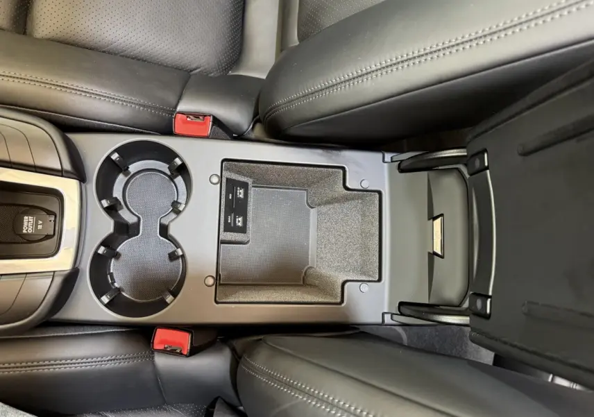 Vue plongeante sur la console centrale noire du Porsche Macan 3.0 S 2019 avec porte-gobelets et rangement ouvert.