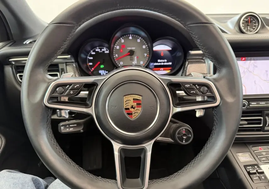 Vue rapprochée du volant cuir et alu multifonctions du Porsche Macan 3.0 S avec tableau de bord et écran tactile visible.