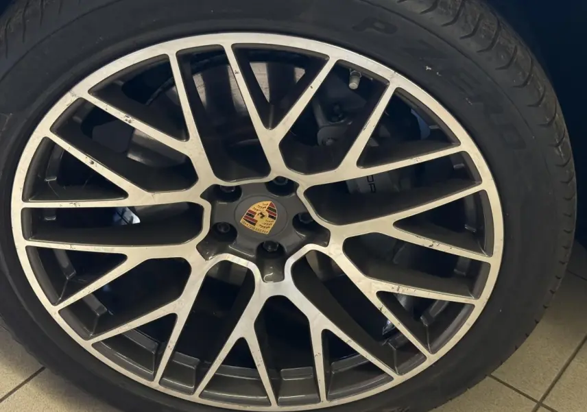 Gros plan sur la jante alliage bicolore d'une Porsche Macan 3.0 S gris foncé avec logo Porsche au centre.