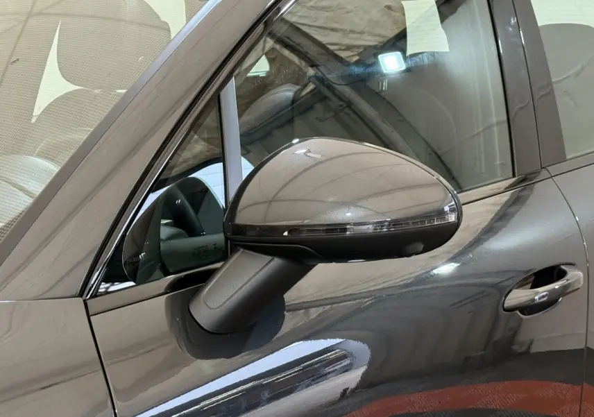 Gros plan sur le rétroviseur côté gauche d’un Porsche Macan 3.0 S gris foncé avec poignée de porte visible.