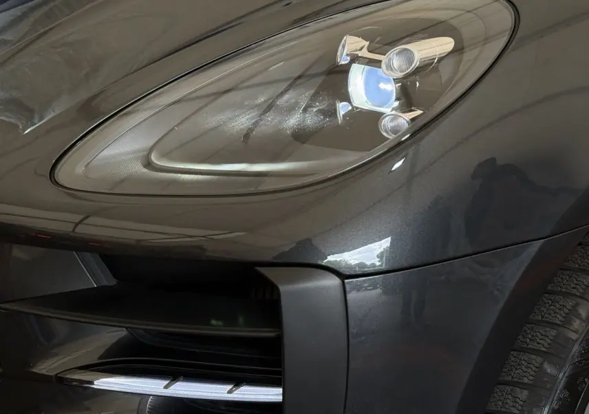 Gros plan sur le phare avant droit du Porsche Macan 3.0 S gris foncé, mettant en valeur le design LED et la calandre.