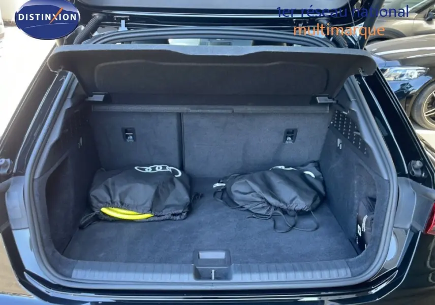 Coffre ouvert d'une Audi A3 Sportback 40 TFSIe noir mito metal, vue arrière montrant un espace de chargement propre avec accessoires.
