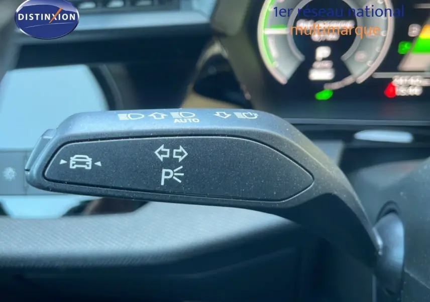 Gros plan sur le commodo de clignotant noir à l'intérieur de l'Audi A3 Sportback 2025, avec tableau de bord numérique en arrière-plan.