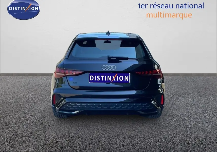 Vue arrière d'une Audi A3 Sportback noire Mito Metal 2025 avec feux LED et logo distinctif sur fond neutre.