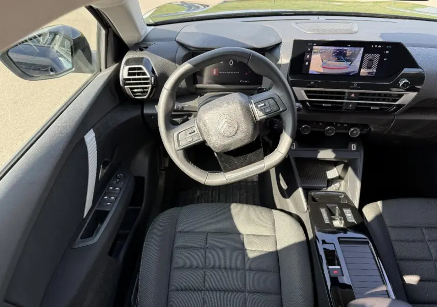 Vue intérieure de face du poste de conduite du Citroën C4 2025, avec volant multifonction et écran tactile central.