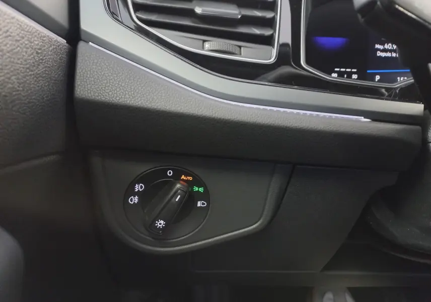Détail de l'intérieur côté gauche du tableau de bord de la Volkswagen Polo Rouge Roi 2025, avec commande d'éclairage en mode automatique.