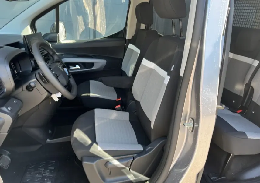 Vue intérieure côté conducteur du Citroën Berlingo 2025 gris Artense, montrant les sièges bi-ton et le volant.