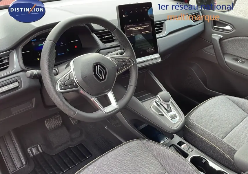 Intérieur moderne du Renault Captur E-Tech 2025, vue du poste de conduite avec volant multifonction et écran tactile vertical.