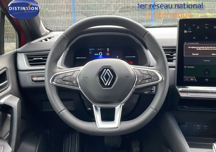 Vue frontale du volant multifonction gris avec logo Renault, tableau de bord numérique et écran tactile du Renault Captur E-Tech 2025.
