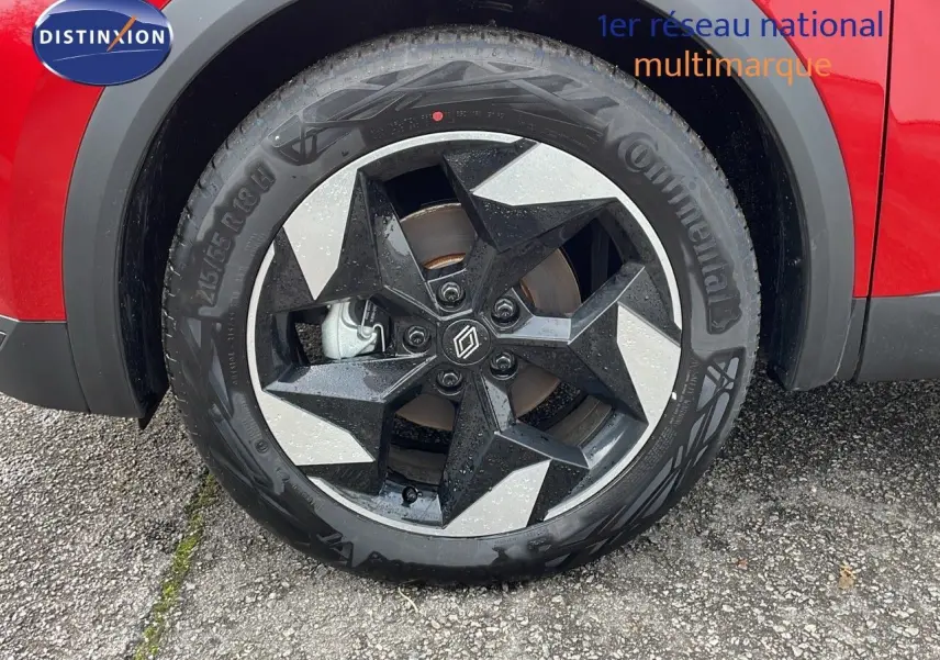 Gros plan sur la roue avant gauche du Renault Captur rouge passion avec jante alliage bicolore noire et argent.