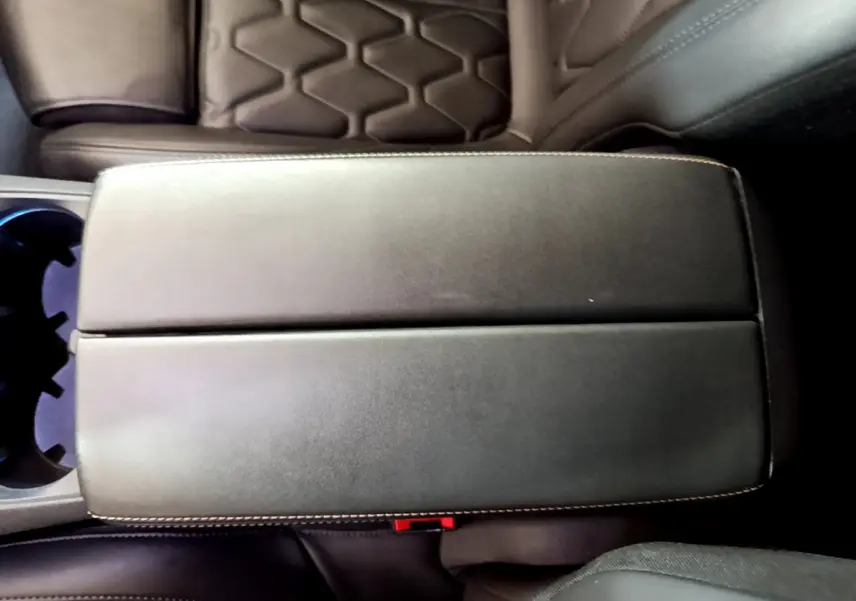 Vue rapprochée de l'accoudoir central en cuir noir avec surpiqûres blanches dans un Peugeot 5008 GT bleu.