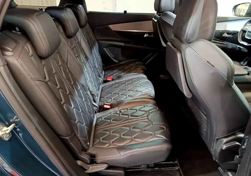 Vue latérale intérieure des sièges arrière en cuir noir du Peugeot 5008 GT bleu, avec motifs géométriques et appuie-têtes.