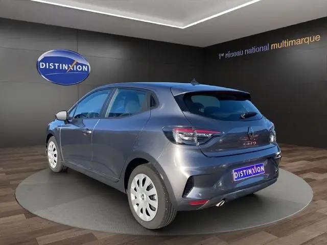 Vue 3/4 arrière droite d'une Renault Clio V gris schiste avec enjoliveurs 16 pouces en tôle, dans un showroom.