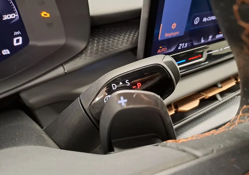 Gros plan sur la commande de boîte automatique et palettes au volant du CUPRA TERRAMAR 2025, intérieur noir avec surpiqûres orange.