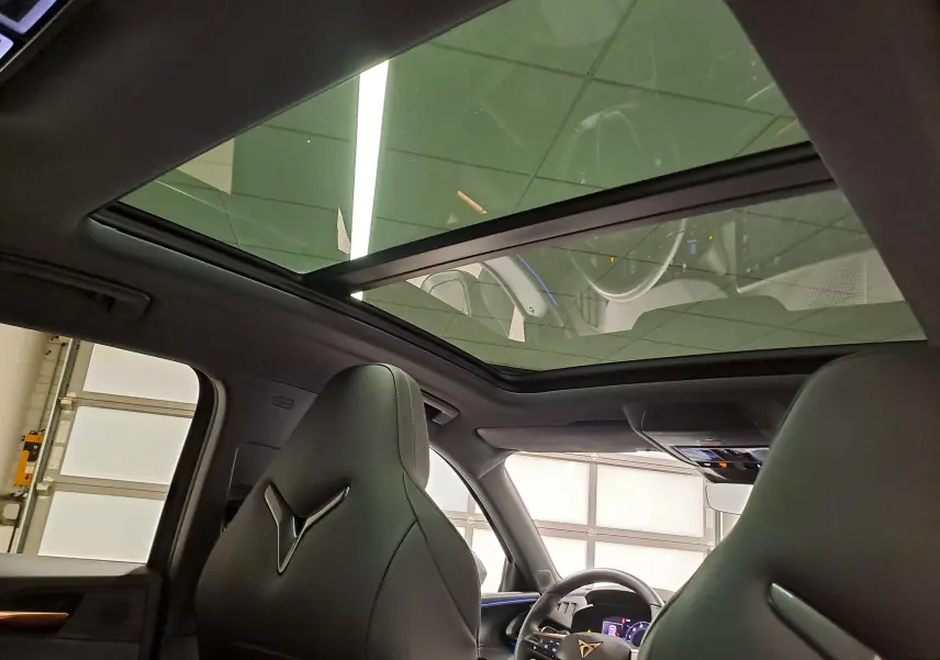 Vue intérieure du toit ouvrant panoramique du CUPRA TERRAMAR 2025, avec sièges noirs et tableau de bord partiellement visible.