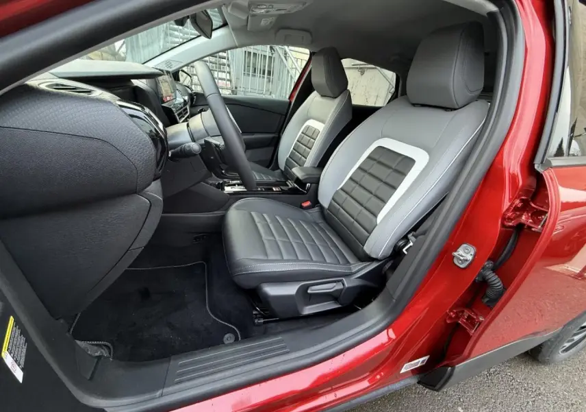Vue intérieure côté conducteur du Citroën C4 rouge elixir 2025, avec sièges bi-ton gris et noir en cuir.