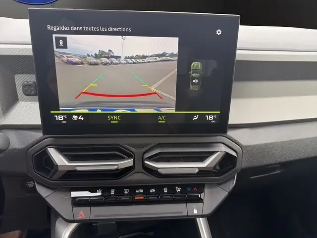 Vue intérieure du tableau de bord du Dacia Bigster gris foncé, écran tactile affichant la caméra de recul et commandes climatisation.