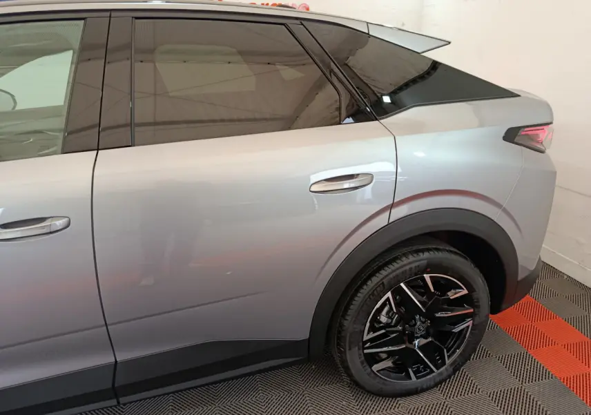 Vue latérale droite du Peugeot 3008 gris clair 2025, mettant en valeur la roue arrière noire et les vitres teintées.