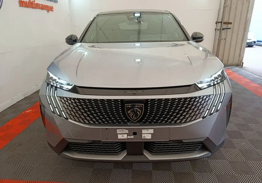 Vue frontale du Peugeot 3008 gris clair 2025 avec calandre distinctive et feux LED verticaux allumés