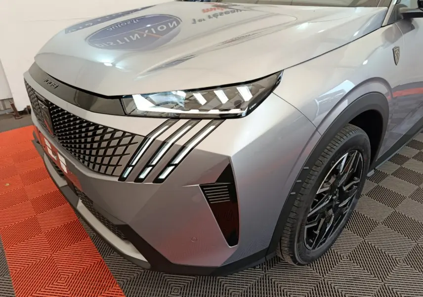 Vue 3/4 avant droit d'un Peugeot 3008 gris clair avec phares LED distinctifs et jantes noires brillantes.